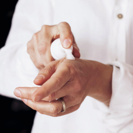 A close up photo of a woman's hands applying moisturizing cream to her hands.