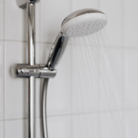 A close up photo of a bathroom shower head with with water coming out of it.